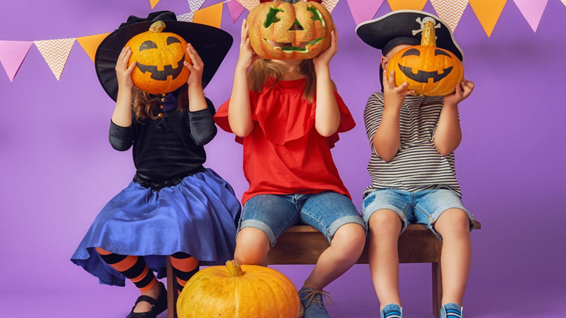 Children holding carved pumpkins in front of their faces